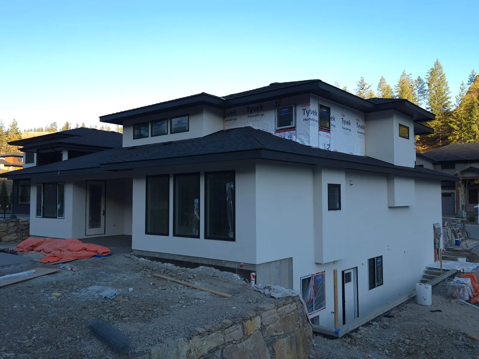 Side elevation of Lot 42 with finished stucco on the main level above a stone retaining wall.
