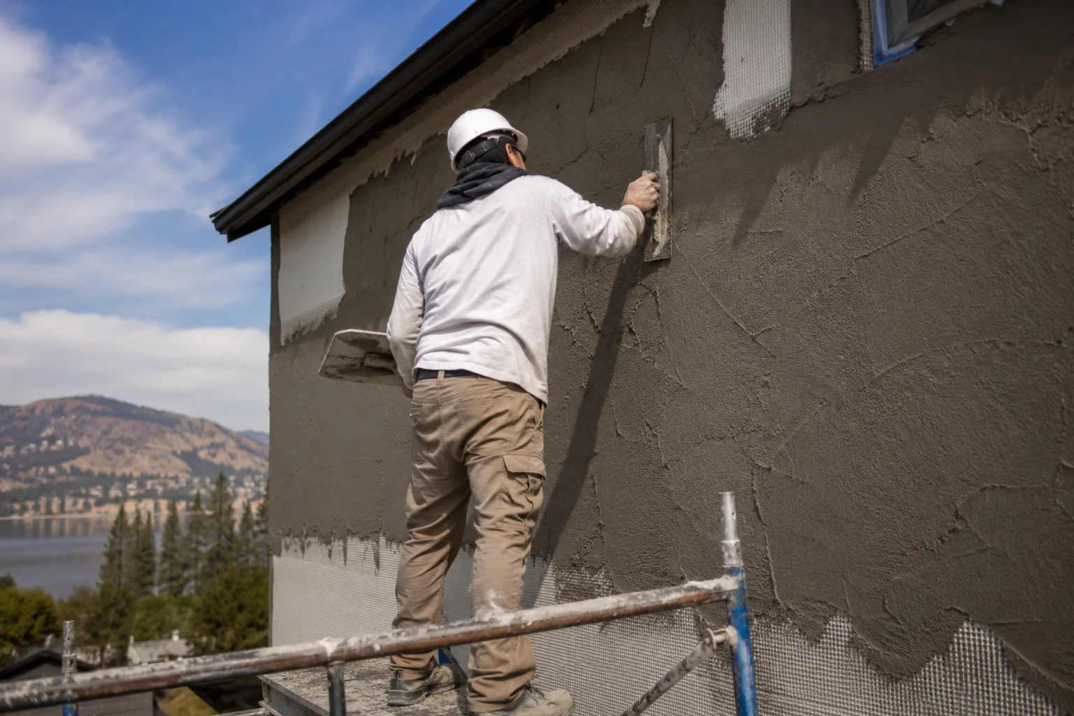 A crew member on a ladder finishing an upper wall.