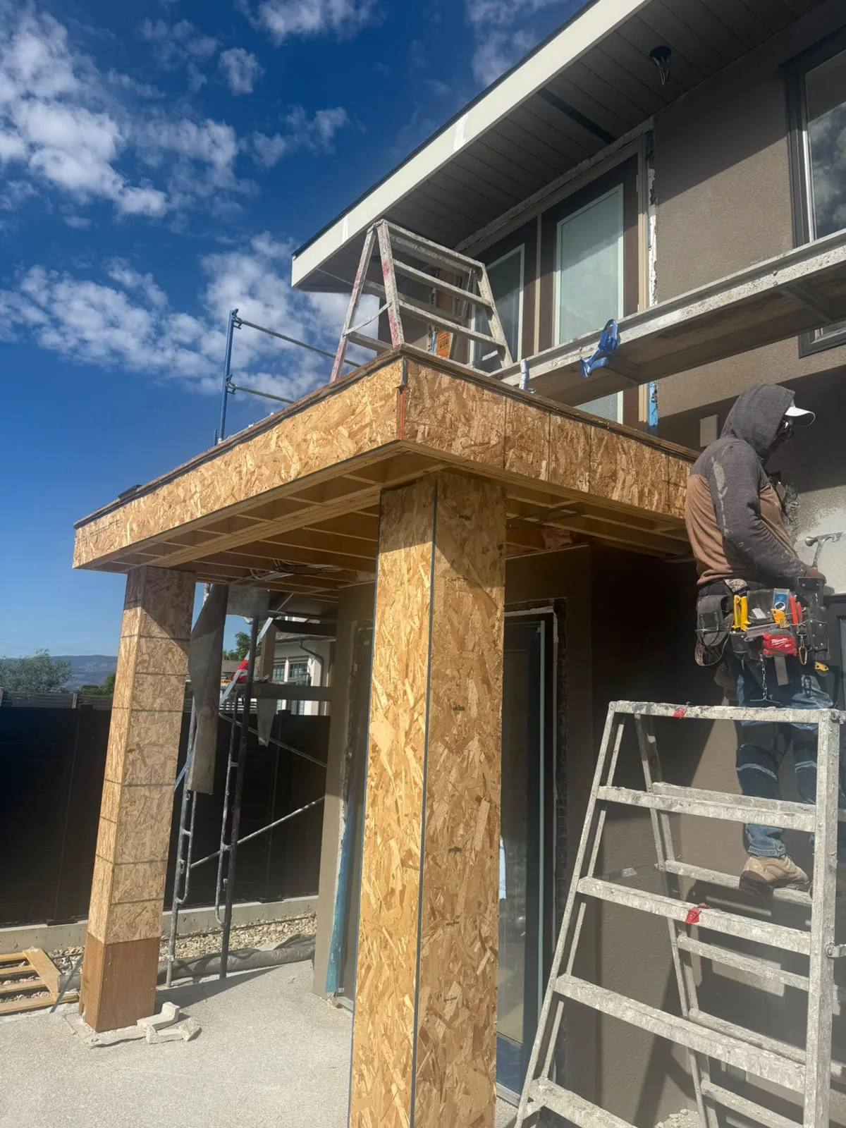 A crew member working an upper wall while the soffit above is framed.